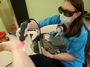 A laser technician treating a patient's heel with the Mphi5 therapy laser.