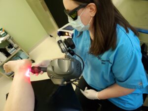 A laser technician treating a patient's heel with the Mphi5 therapy laser.