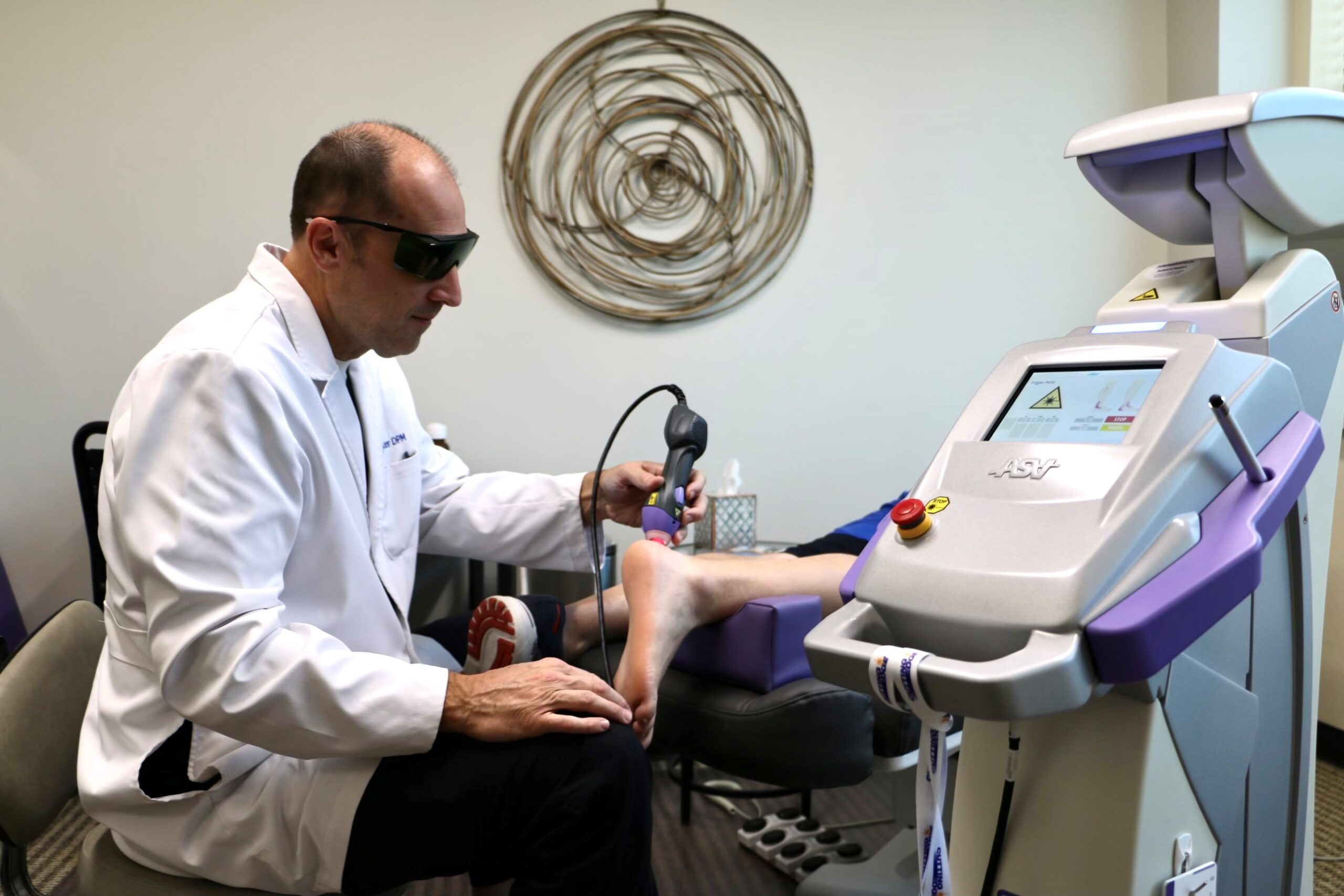 Dr. Joel Foster treating a patient's Achilles tendon with the M7 MLS Therapy Laser