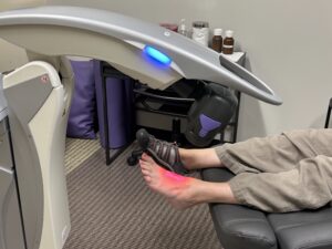 A patient receives laser therapy treatment on the top of her foot with the M7 MLS Therapy Laser at Dr. Foster's practice.